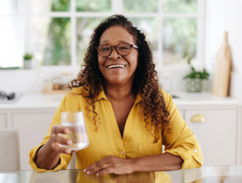 Senior woman drinking water at home.